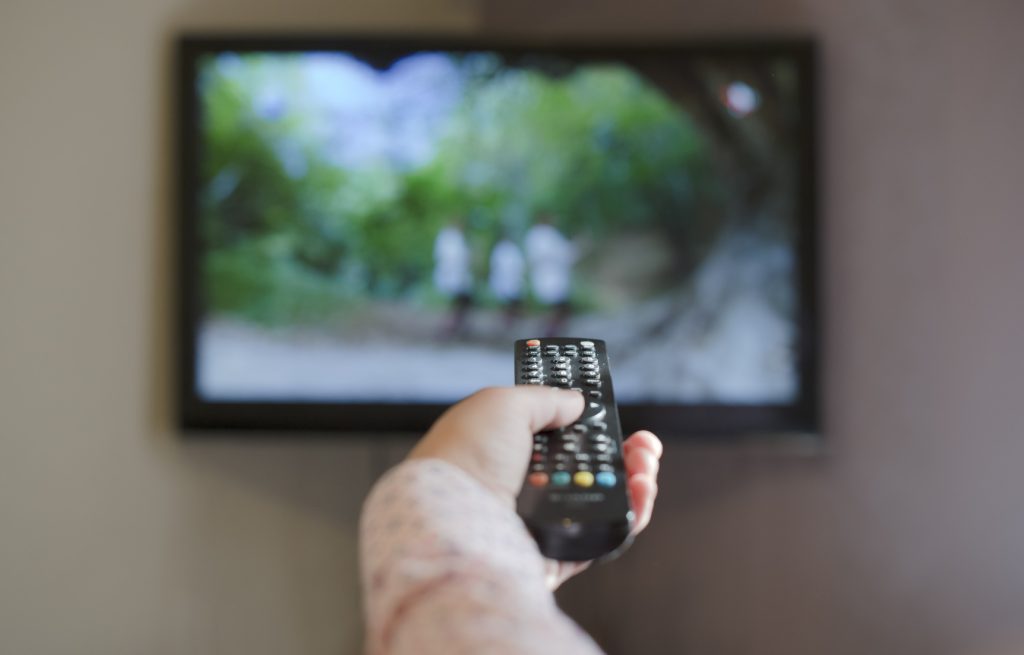 Segurando controle remoto da TV.